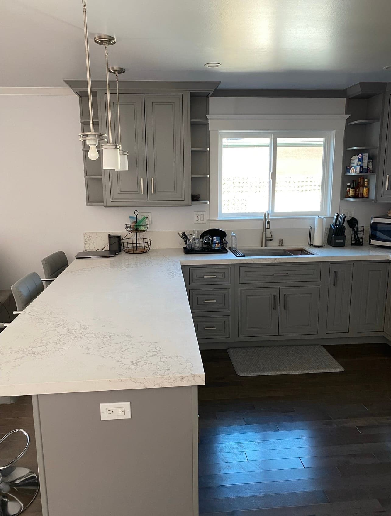 Finished ADU kitchen with gray cabinetry and stone breakfast bar