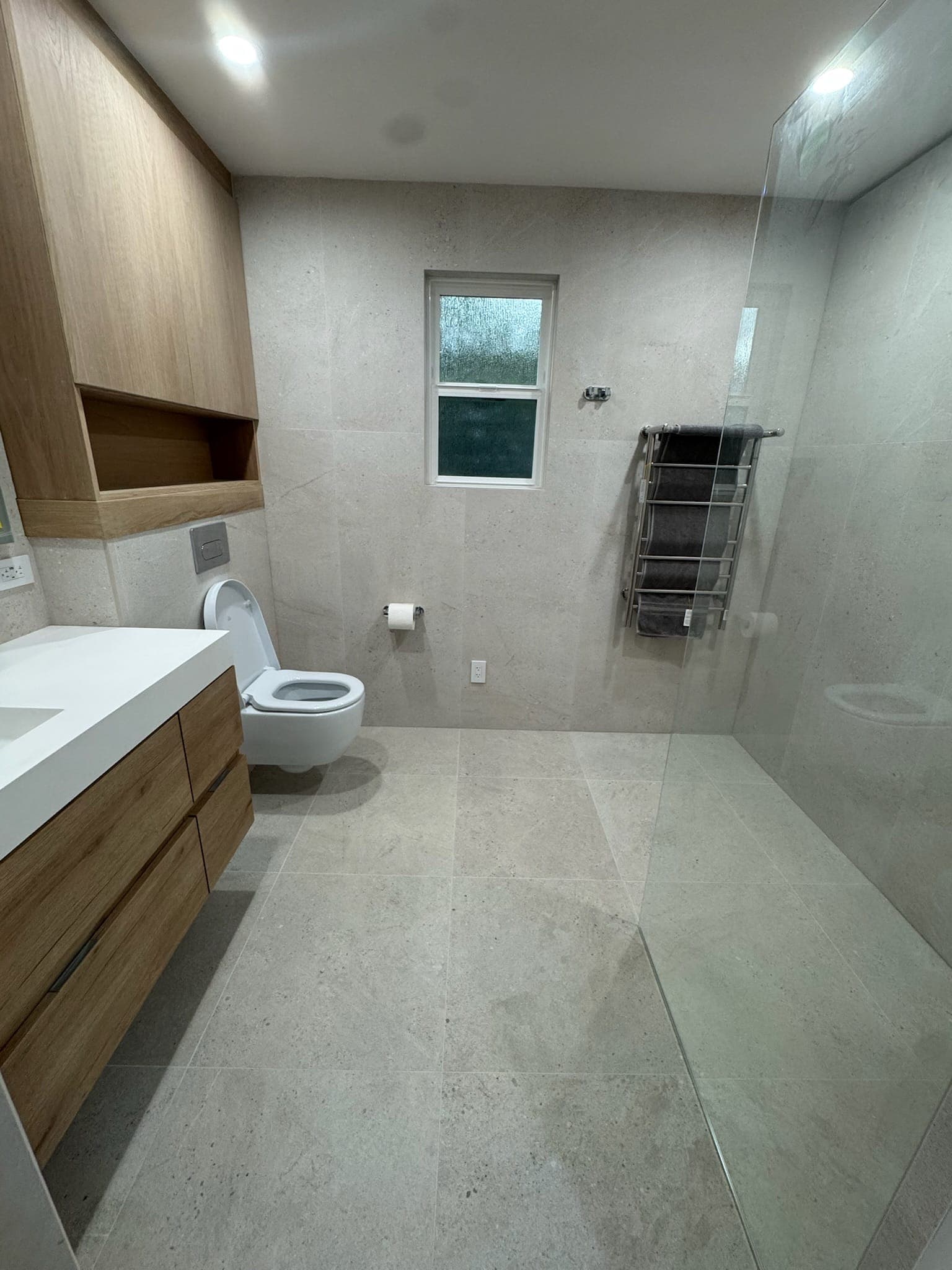 Wide view of the finished master bathroom with curbless shower, towel warmer, and floating vanity